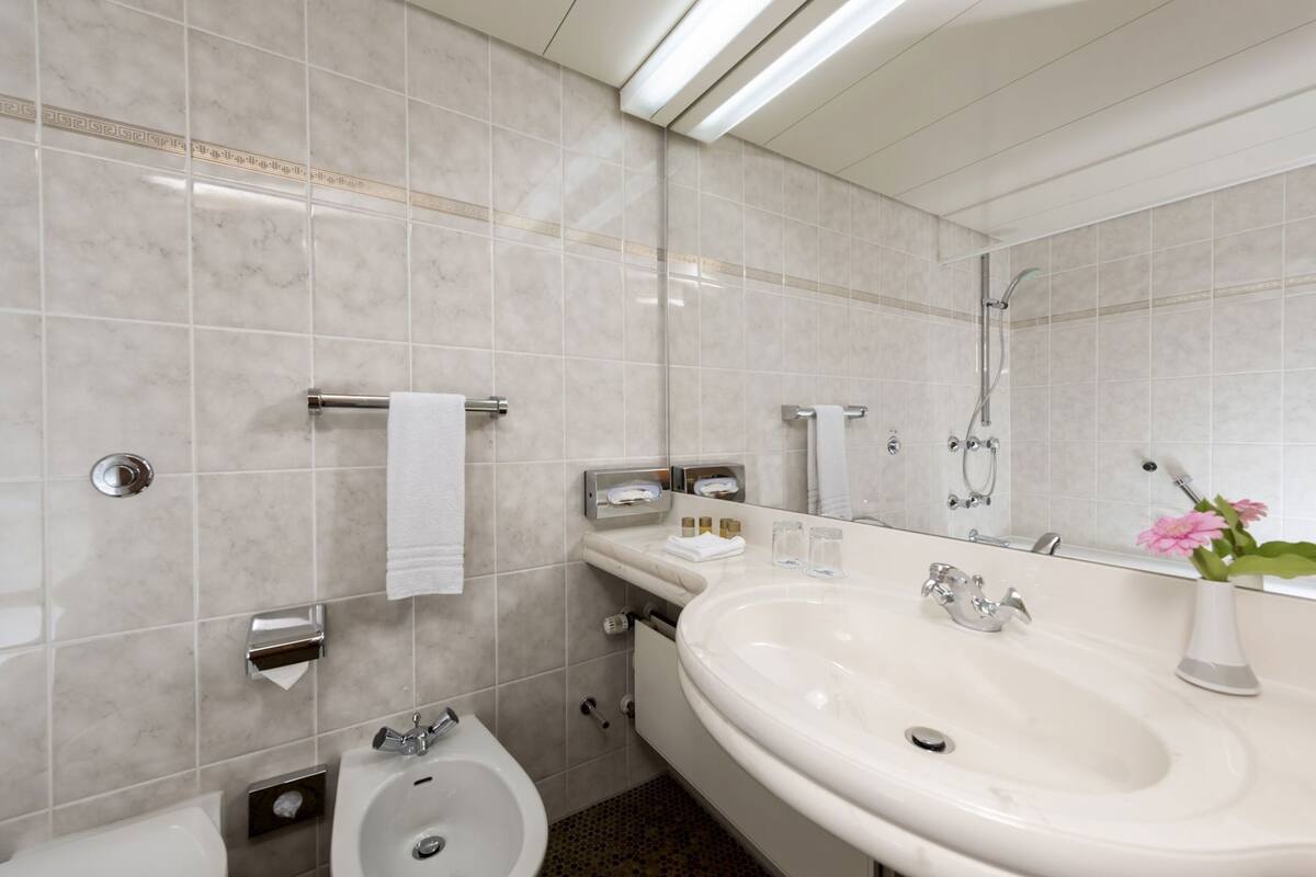 A modern bathroom with a large sink, mirror, and shower.