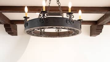 Un comedor con mesa de madera, sillas, un candelabro, chimenea y una orquídea en maceta.