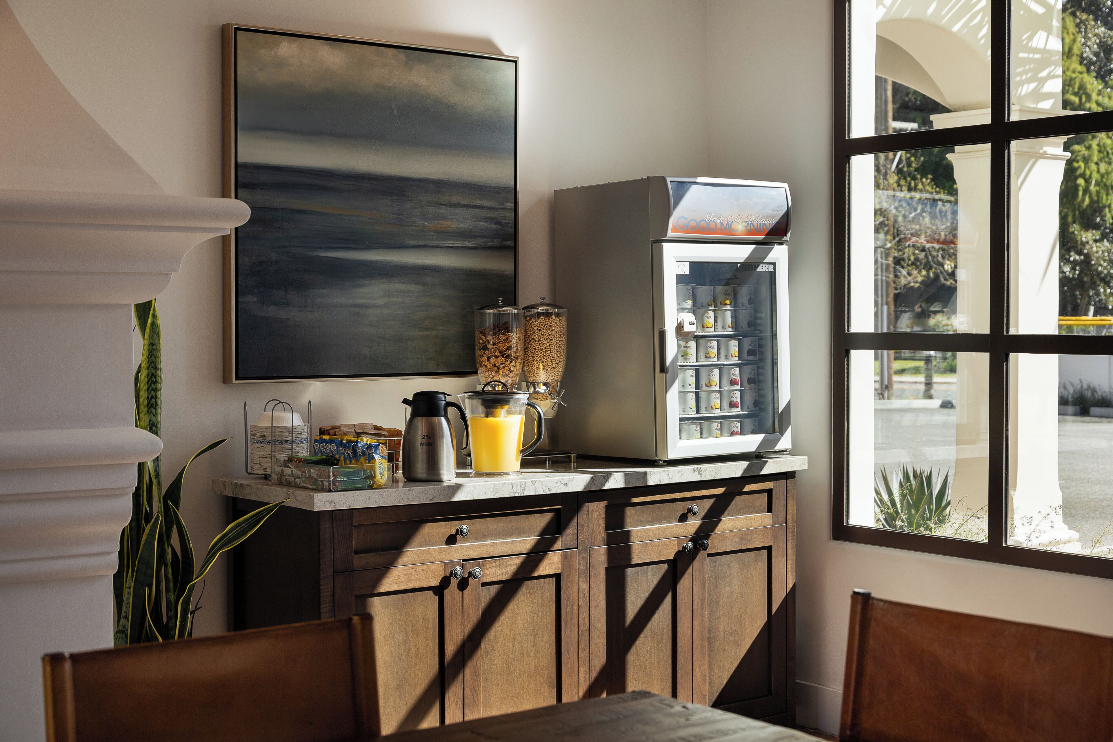 A kitchen with a coffee maker, a blender, and a window with a view of the outside.