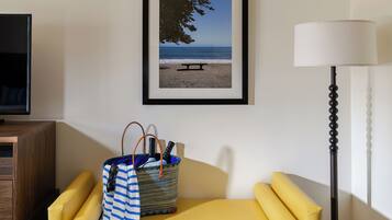 A yellow sofa, a framed beach photo, a lamp, and a wooden cabinet.