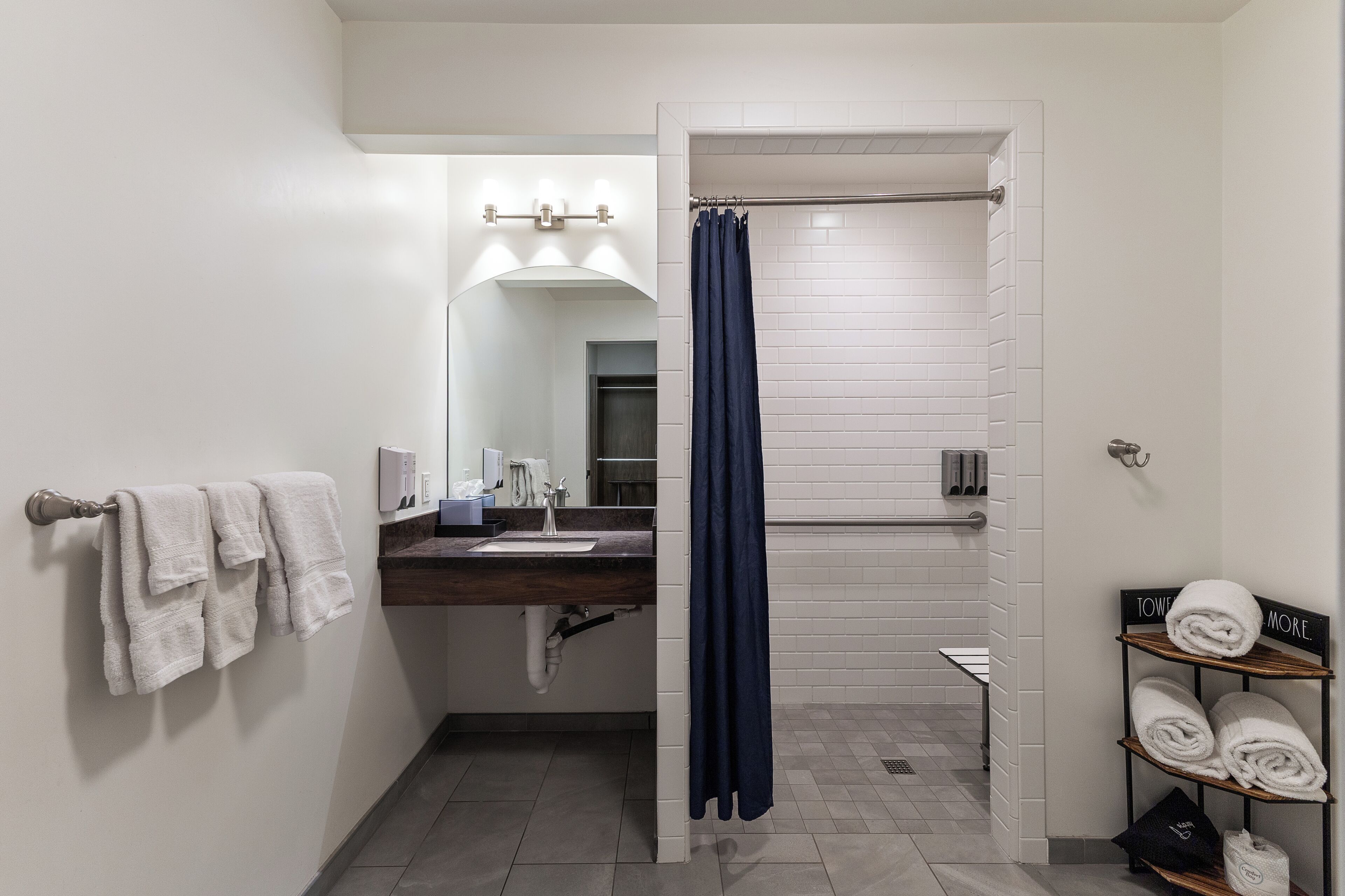 Une salle de bain avec un lavabo blanc, un miroir, un porte-serviettes et un rideau de douche.