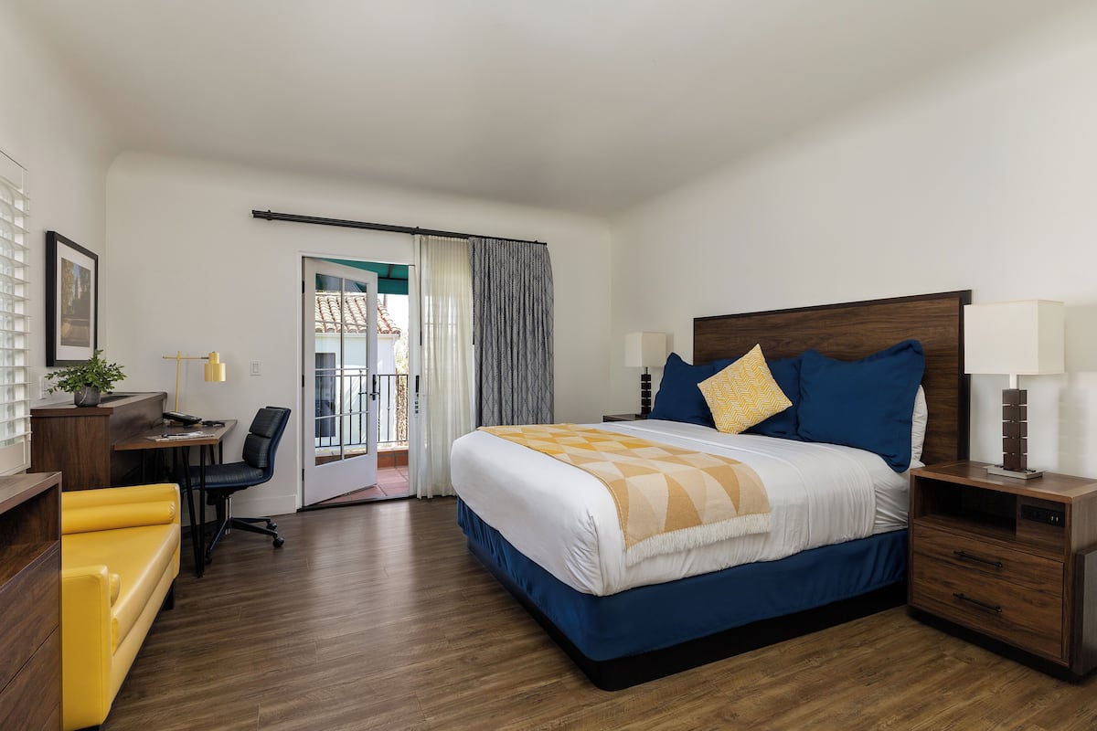 Quarto de hotel com cama, mesas de cabeceira, escrivaninha, poltrona e sofá.