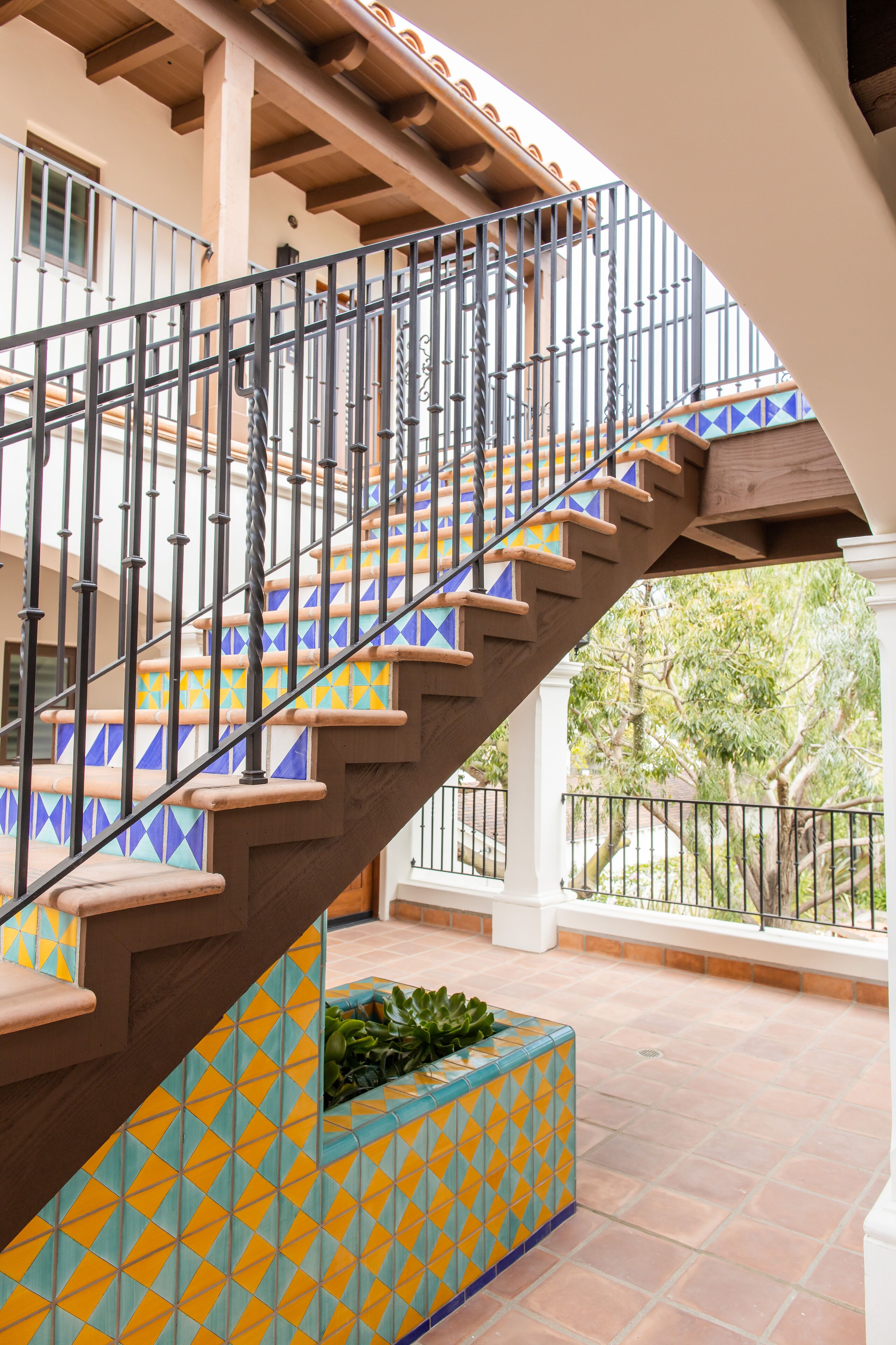 A spiral staircase with a geometric tile pattern on the steps and a metal railing.