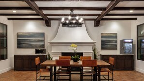 Une salle à manger avec une cheminée, un lustre et un coin cuisine équipé de placards et d’un four à micro-ondes.