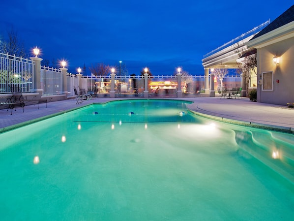Una piscina al aire libre, sillones reclinables de piscina