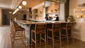 A bar area with wooden bar stools, a counter with bottles, and a potted plant. - Holiday Inn Redding by IHG (Redding)