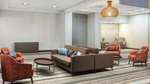 A modern hotel lobby with a brown sofa, red armchairs, and a patterned carpet. - Holiday Inn Redding by IHG (Redding)