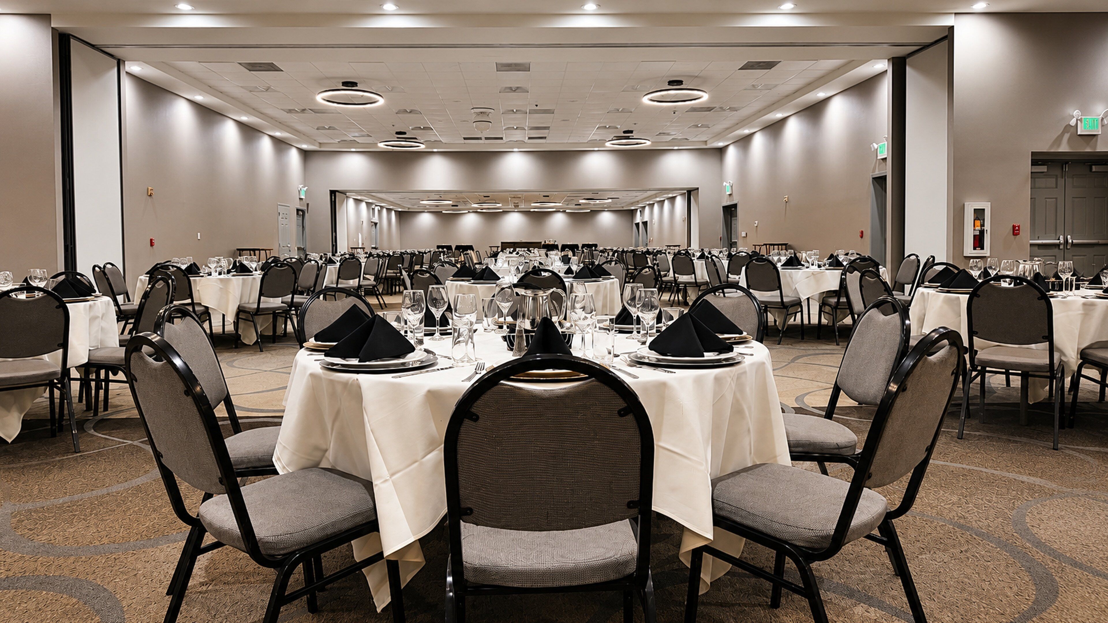 A conference room with round tables, chairs, and banquet-style table settings.