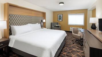 Habitación de hotel con una cama grande, un escritorio con ordenador, una silla y una ventana.