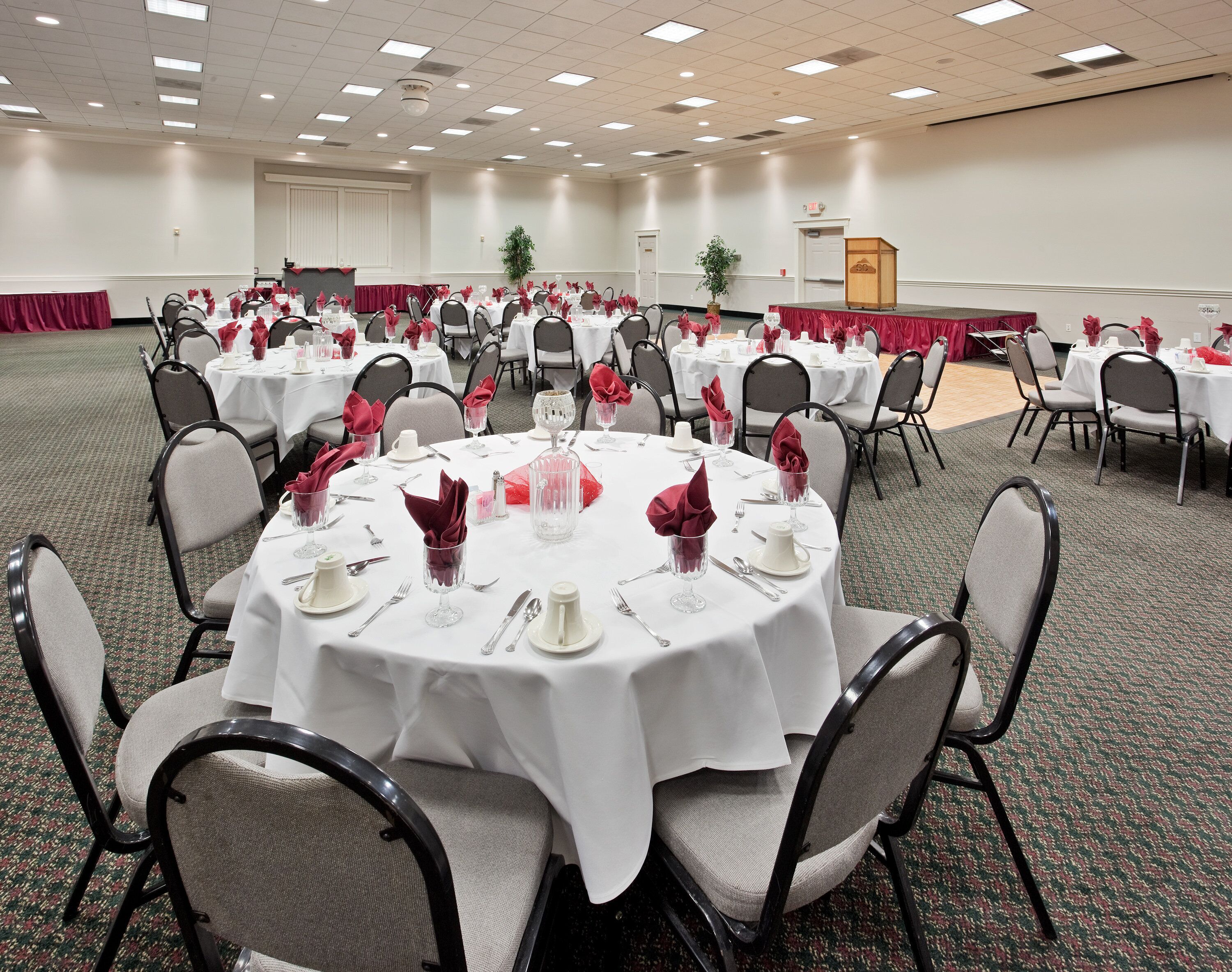 A conference room with round tables, chairs, and a stage area.