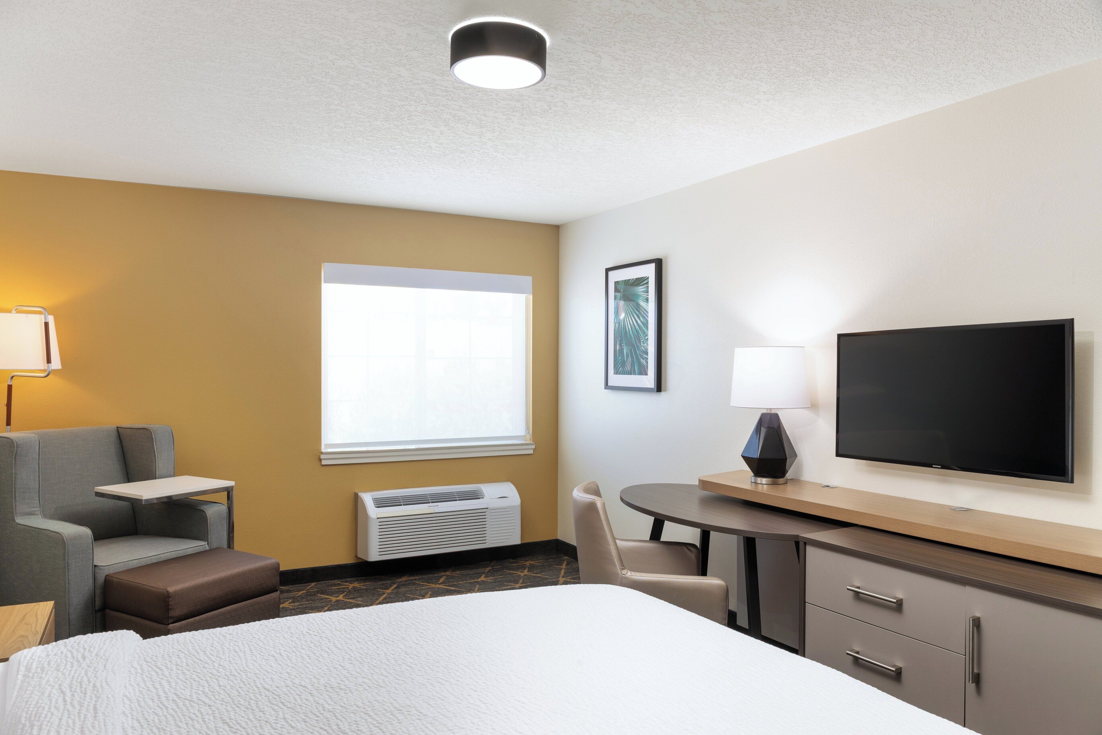 Una habitación de hotel con una cama, un escritorio, una silla, un televisor y una ventana.