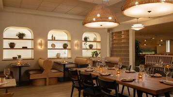 L’intérieur d’un restaurant avec des tables et des chaises en bois, et un éclairage chaleureux.
