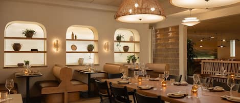 Interior de restaurante con mesas y sillas de madera, e iluminación cálida.