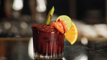 A cocktail with shrimp, lime, and an orange slice on a glass.