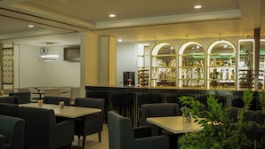 A restaurant with a bar area featuring shelves of bottles and a seating area with tables and chairs. - Hotel El Dorado (Los Mochis)