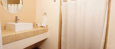 Un baño con lavamanos, espejo, inodoro y cortina de ducha.