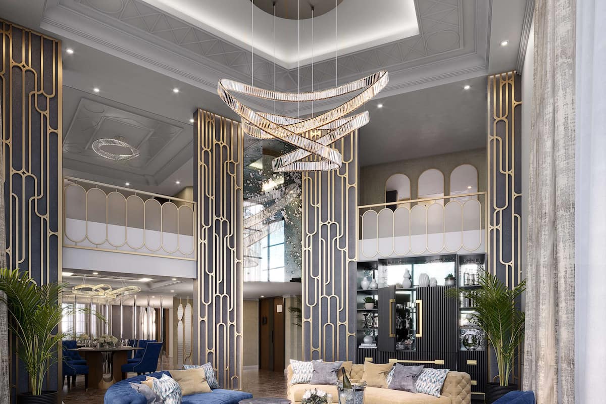 Eine geräumige Lobby mit hoher Decke, einem prunkvollen Chandelier und einer Sitzecke mit blauen Sofas und einem runden Couchtisch.