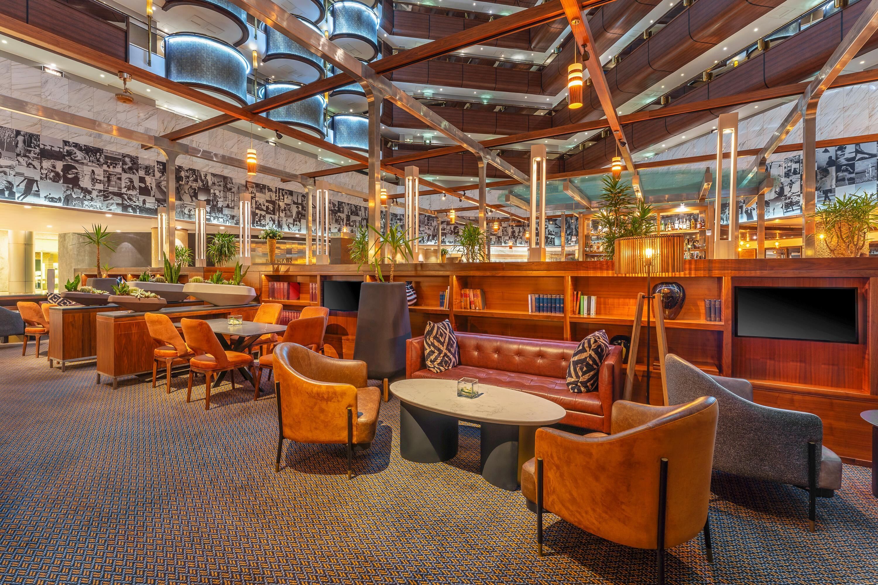 A spacious lounge area with seating arrangements, a bar, and a wall adorned with photographs.