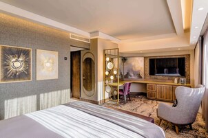 Habitación de hotel con una cama grande, televisión, escritorio y una silla.