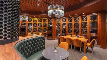 Zona de bar con una mesa redonda, asientos de cuero y una vitrina de vinos.