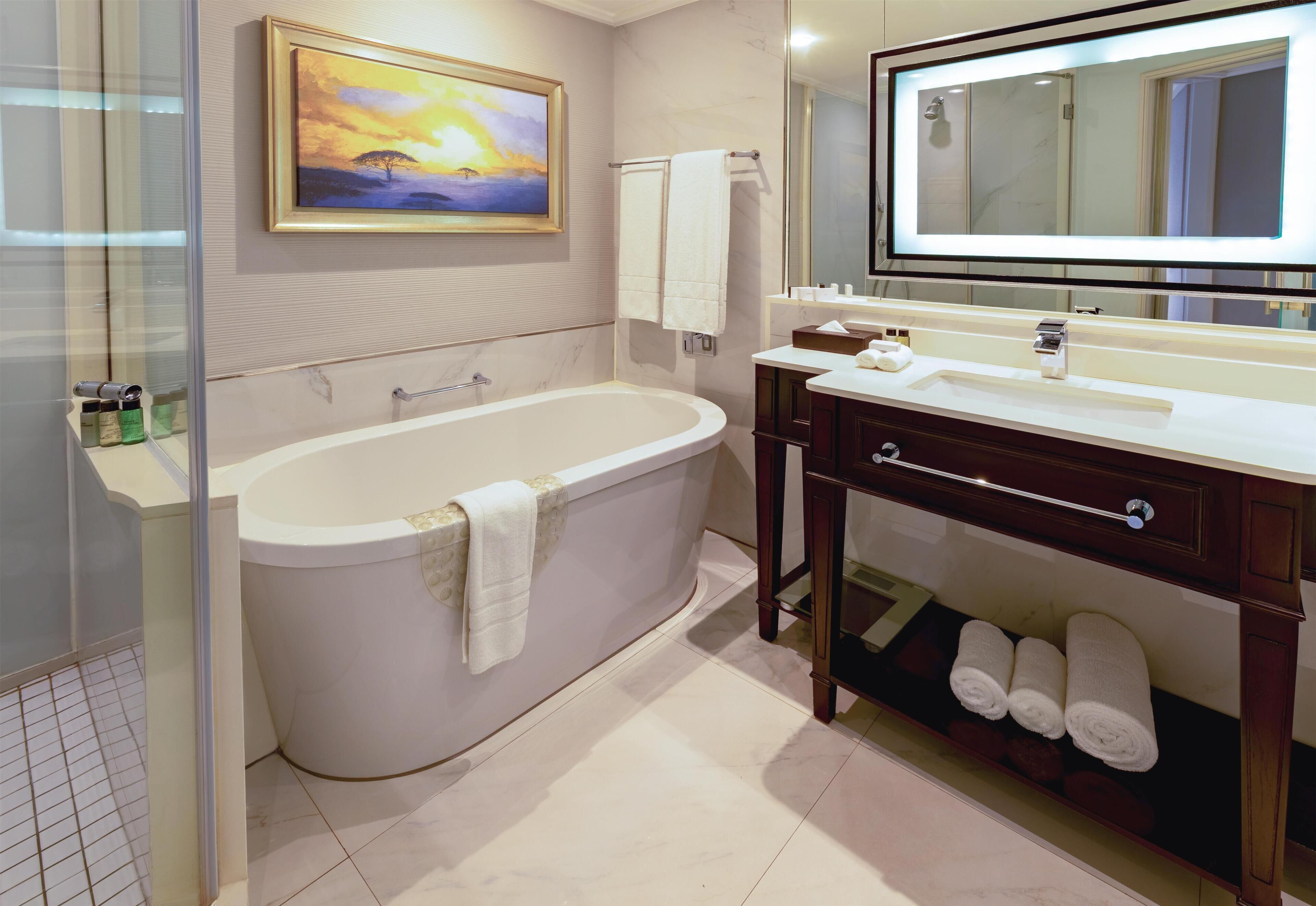 Un baño moderno con una bañera independiente, un espejo grande y una cabina de ducha con paredes de vidrio.