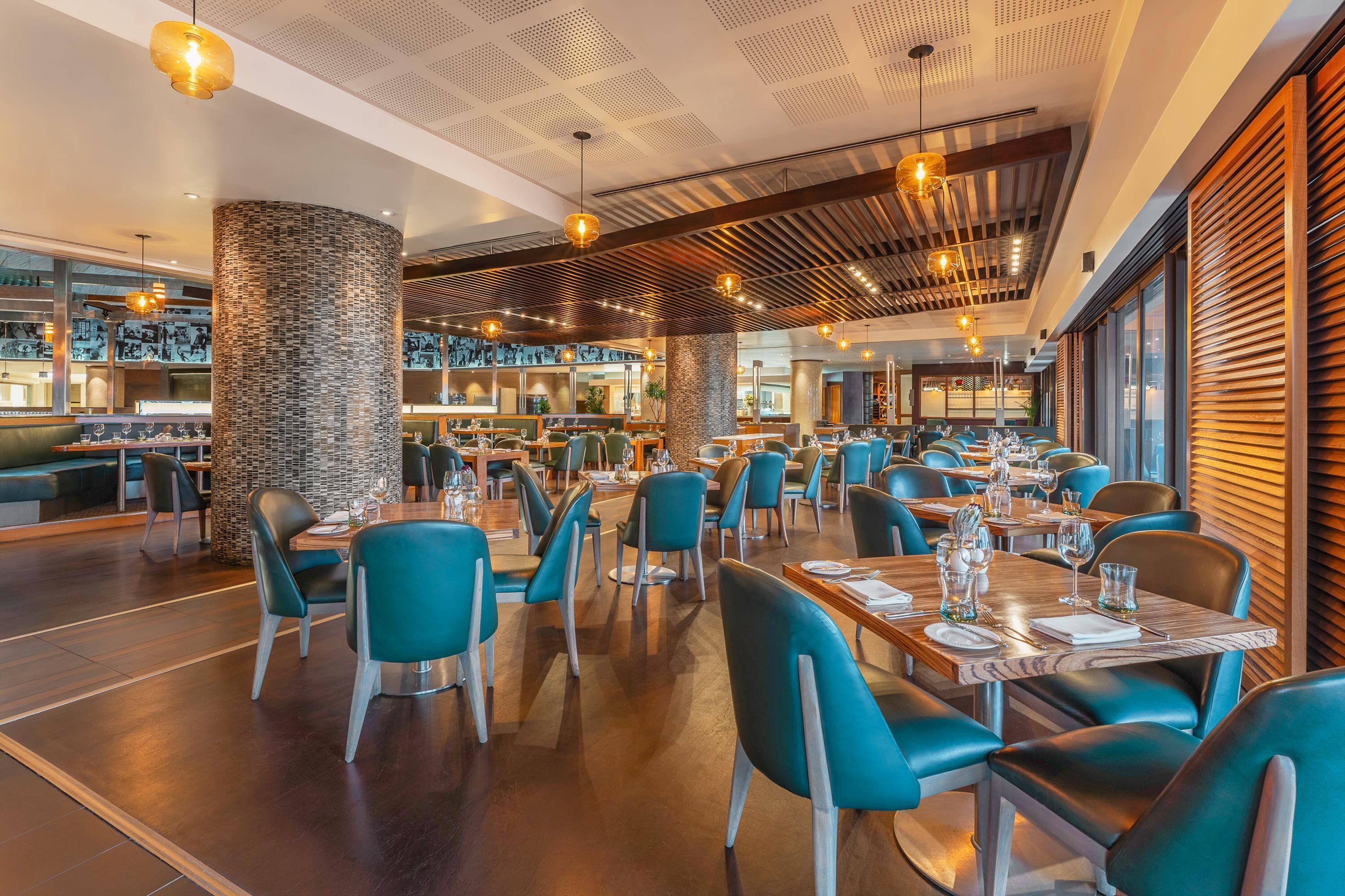 A spacious restaurant with high ceilings, modern lighting, and a variety of seating arrangements.