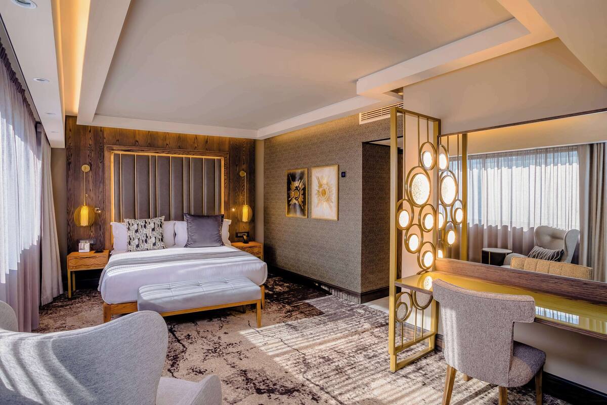 Ein Hotelzimmer mit einem großen Bett, einem Schreibtisch, einem Stuhl und einem Spiegel.