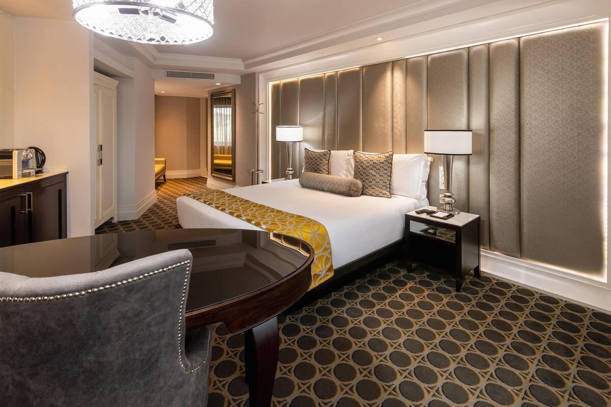 Ein Hotelzimmer mit Bett, Nachttischen, einem Schreibtisch und einem Sessel.