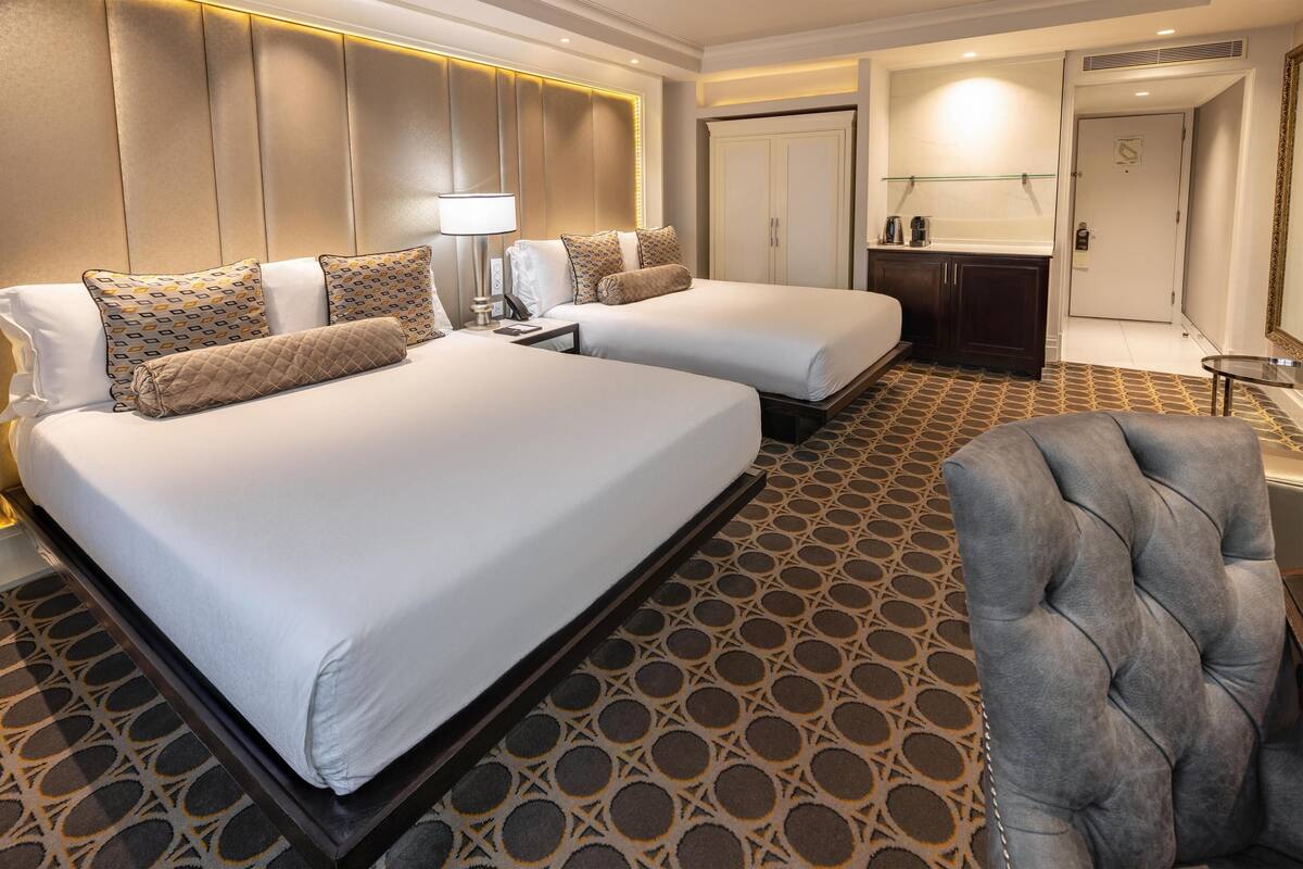 Ein Hotelzimmer mit zwei Betten, einer Sitzecke, einer Minibar und einem Badezimmer.