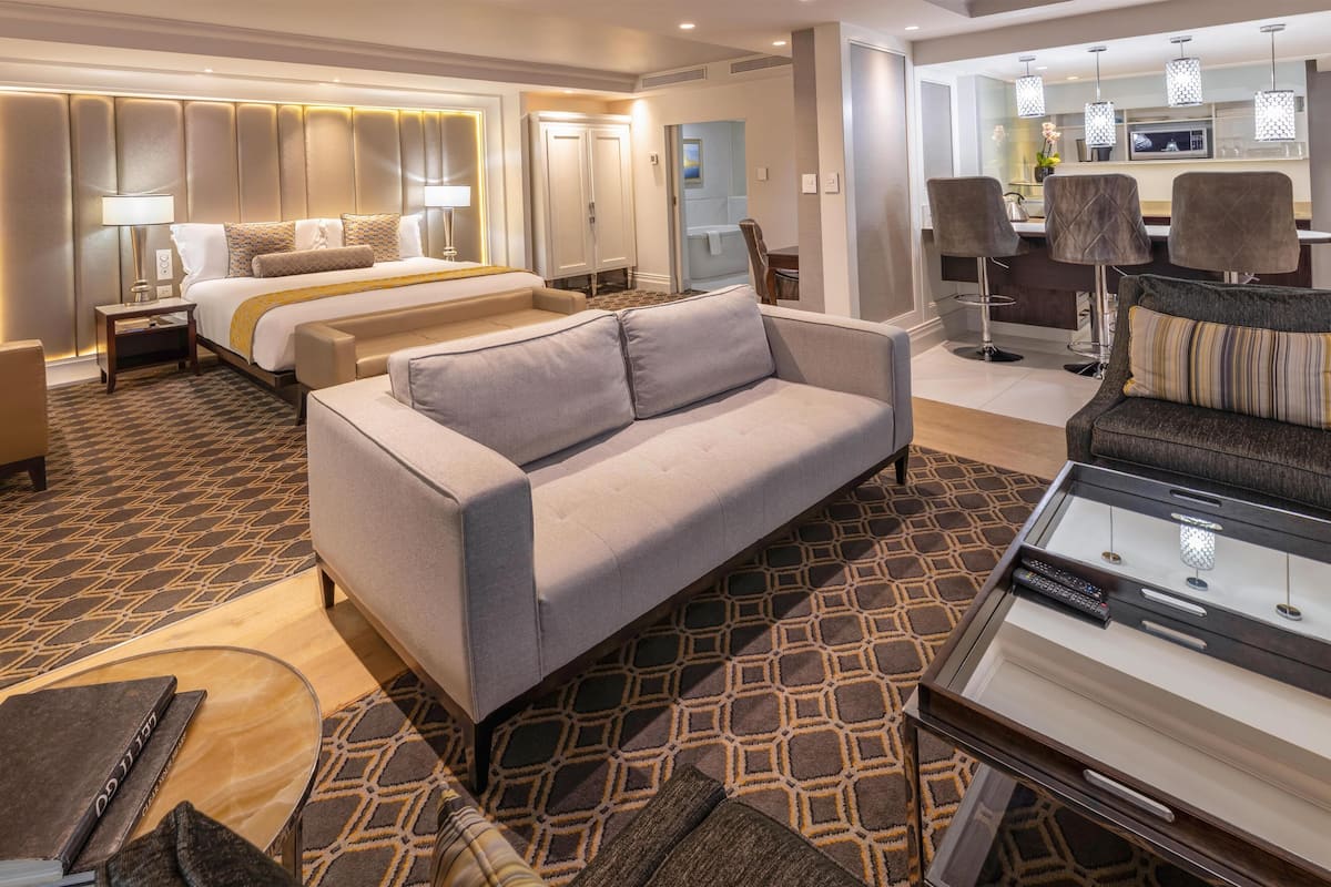 Ein Hotelzimmer mit einem Bett, zwei Sofas, einem Couchtisch und einem Essbereich mit Stühlen.