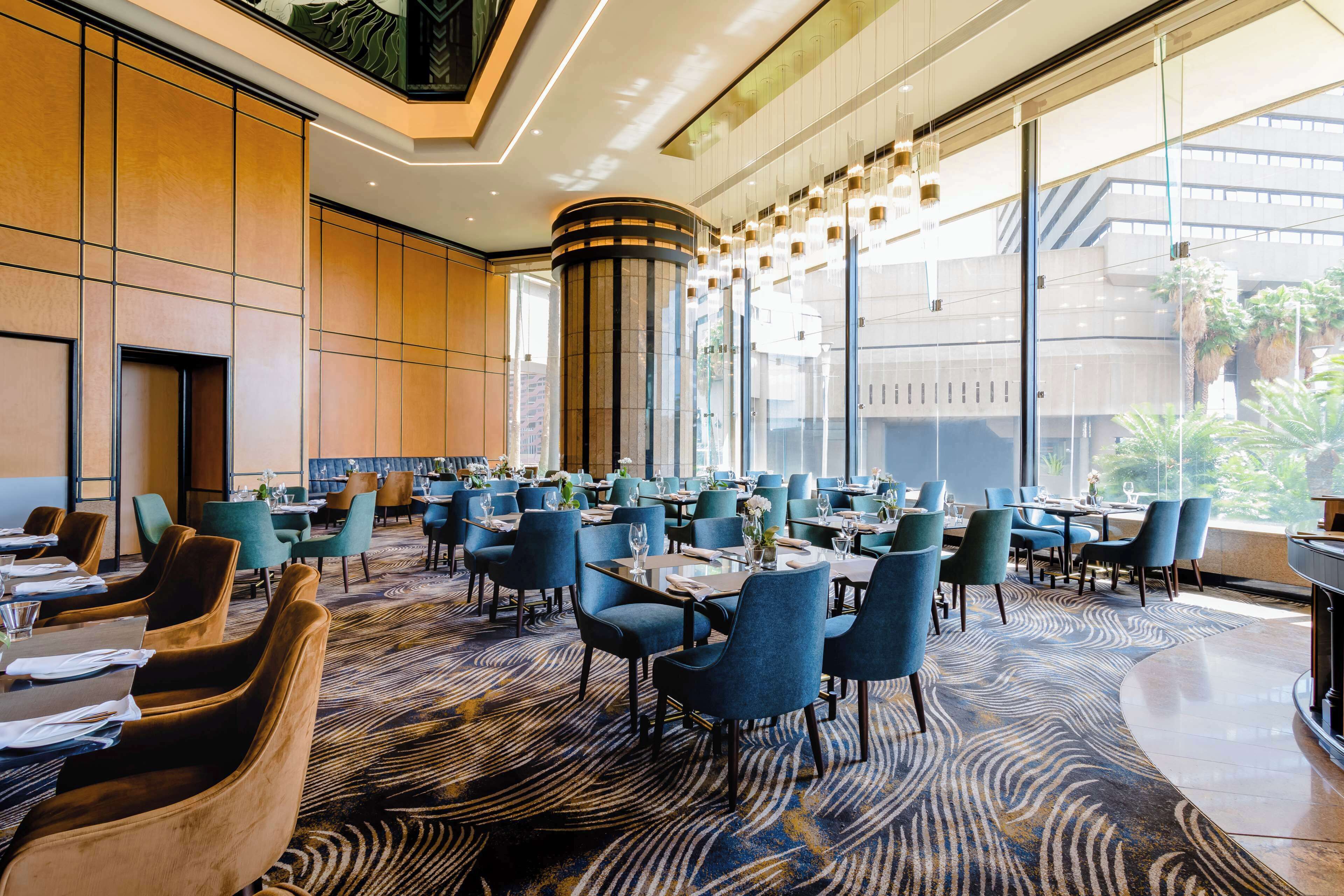 A spacious dining area with high ceilings, large windows, and a modern interior design.