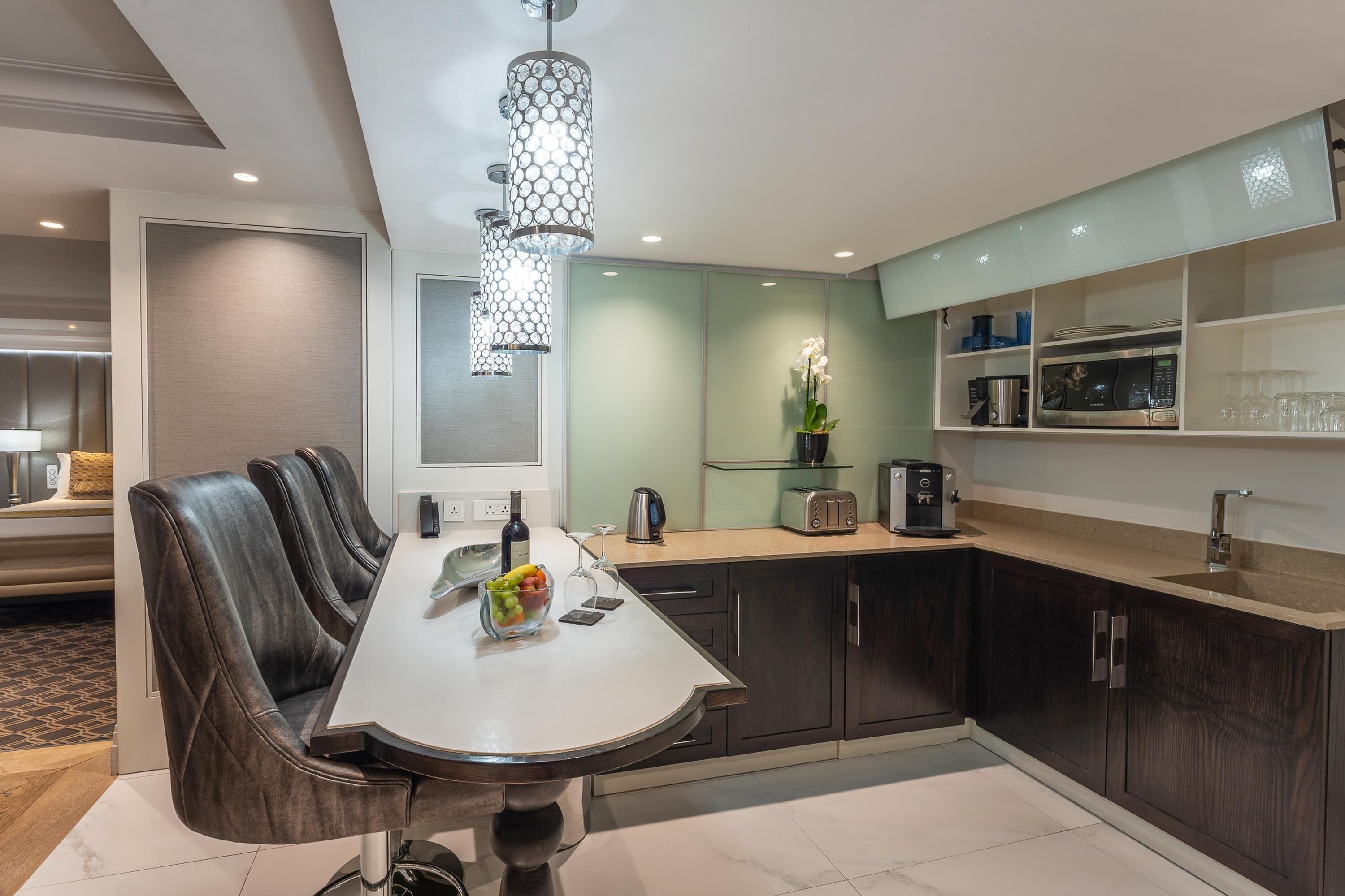A modern kitchen with a dining area, featuring a round table, dark wooden cabinets, and a unique chandelier.