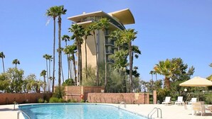 Ein Swimmingpool mit Liegestühlen und Palmen.