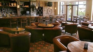 Eine Bar mit Ledersitzgelegenheiten, einem Weinkühlschrank und einem Fernseher.