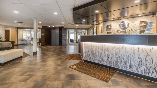 A hotel reception area with a modern design, featuring a reception desk, a sofa, and a patterned rug on the floor. - Comfort Inn & Suites Lexington - Hamburg I-75 (Lexington)