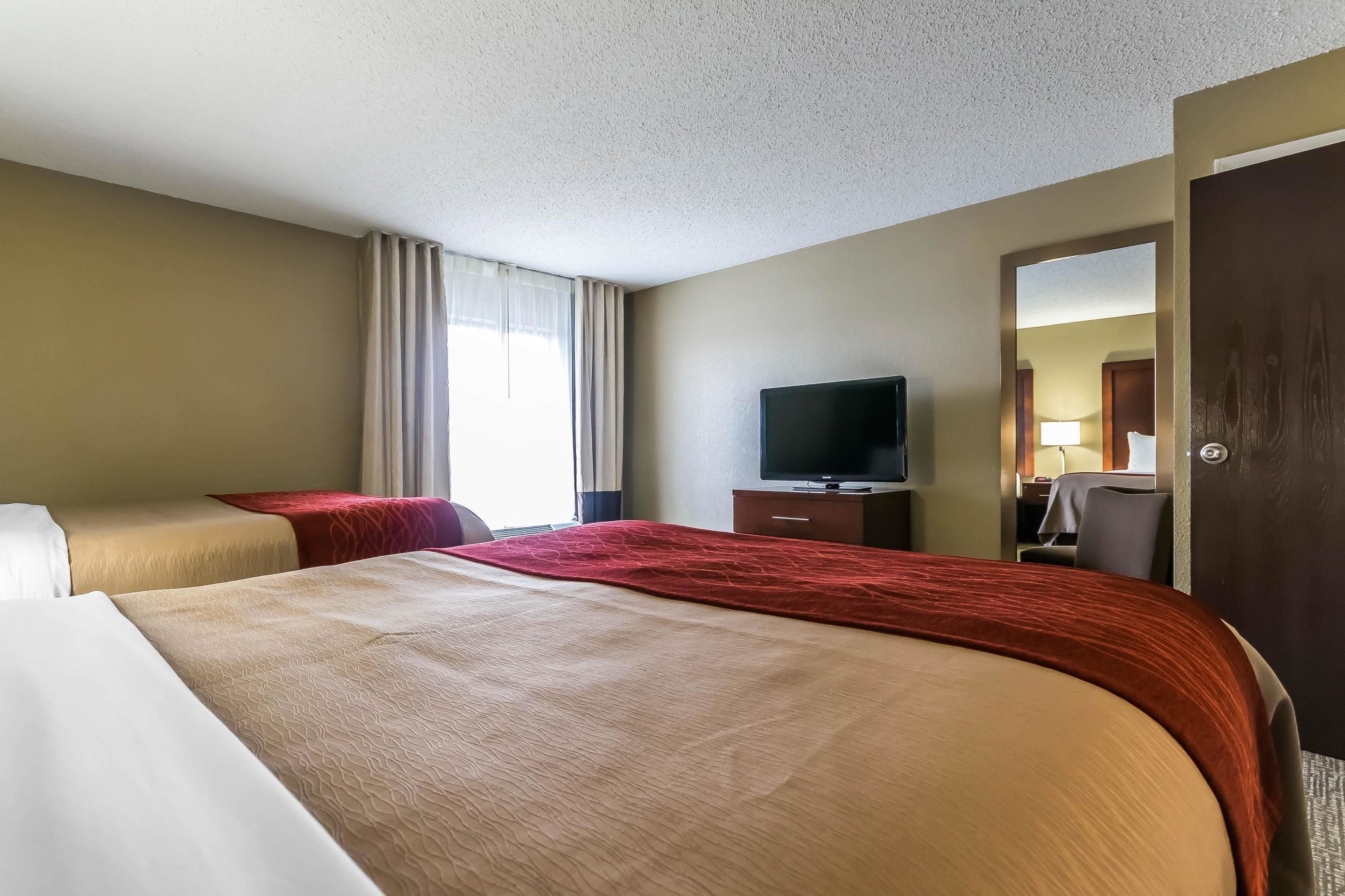A hotel room with a large bed, a TV, a desk, and a chair.