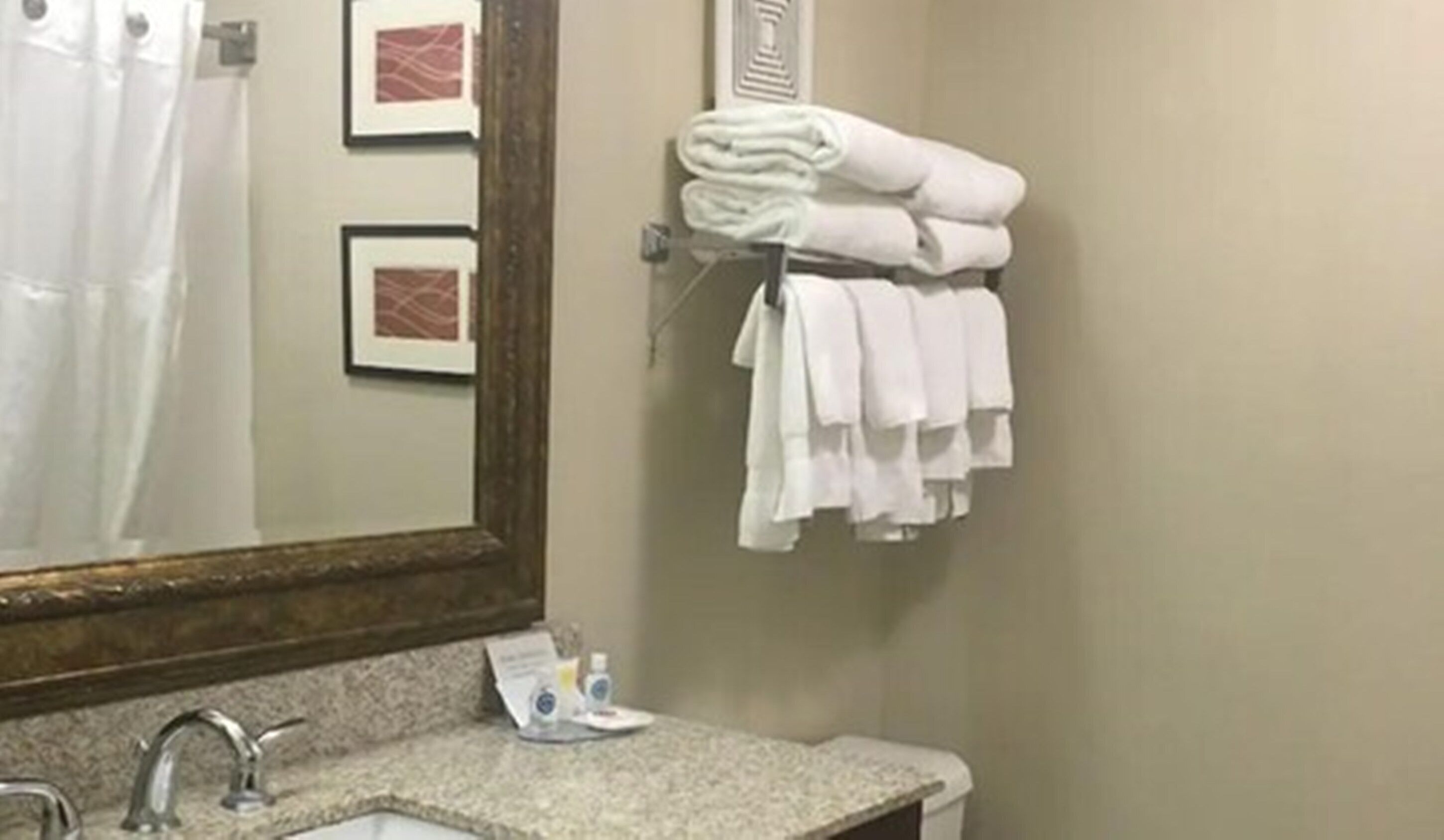 A bathroom with a sink, a mirror, and a towel rack with folded towels.