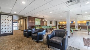 A spacious lobby with leather armchairs, a reception area, and a dining area with green chairs. - Comfort Inn & Suites Lexington - Hamburg I-75 (Lexington)