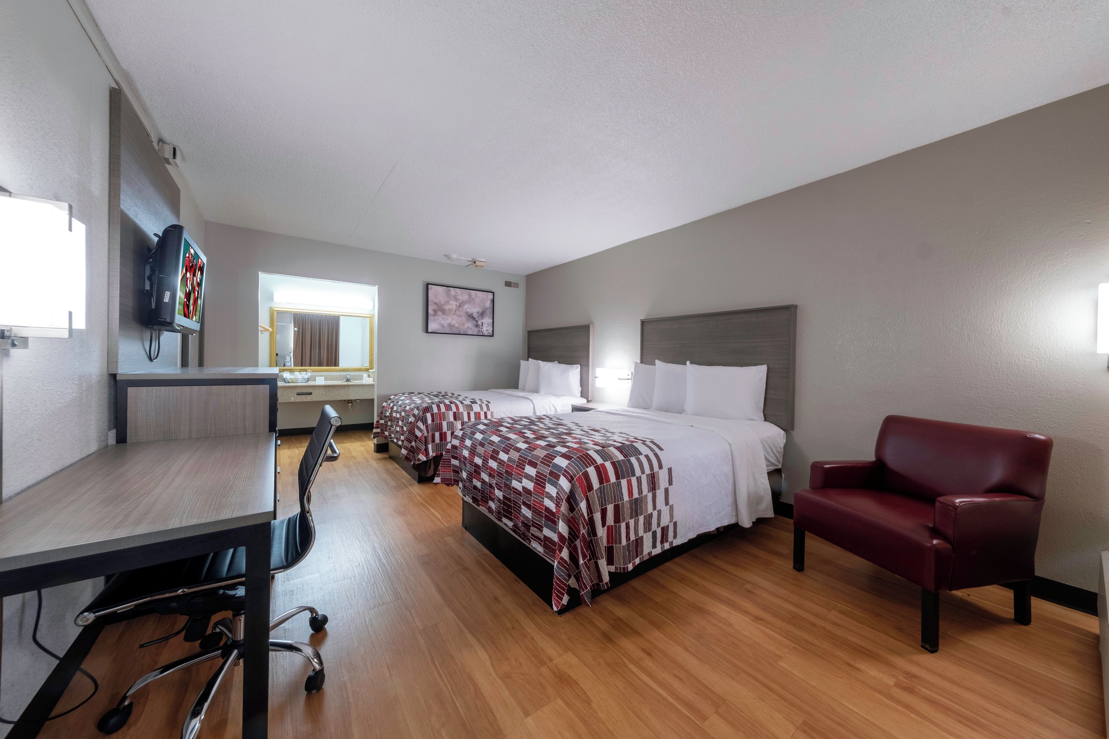 Een hotelkamer met een bed, een bureau, een stoel en een televisie.