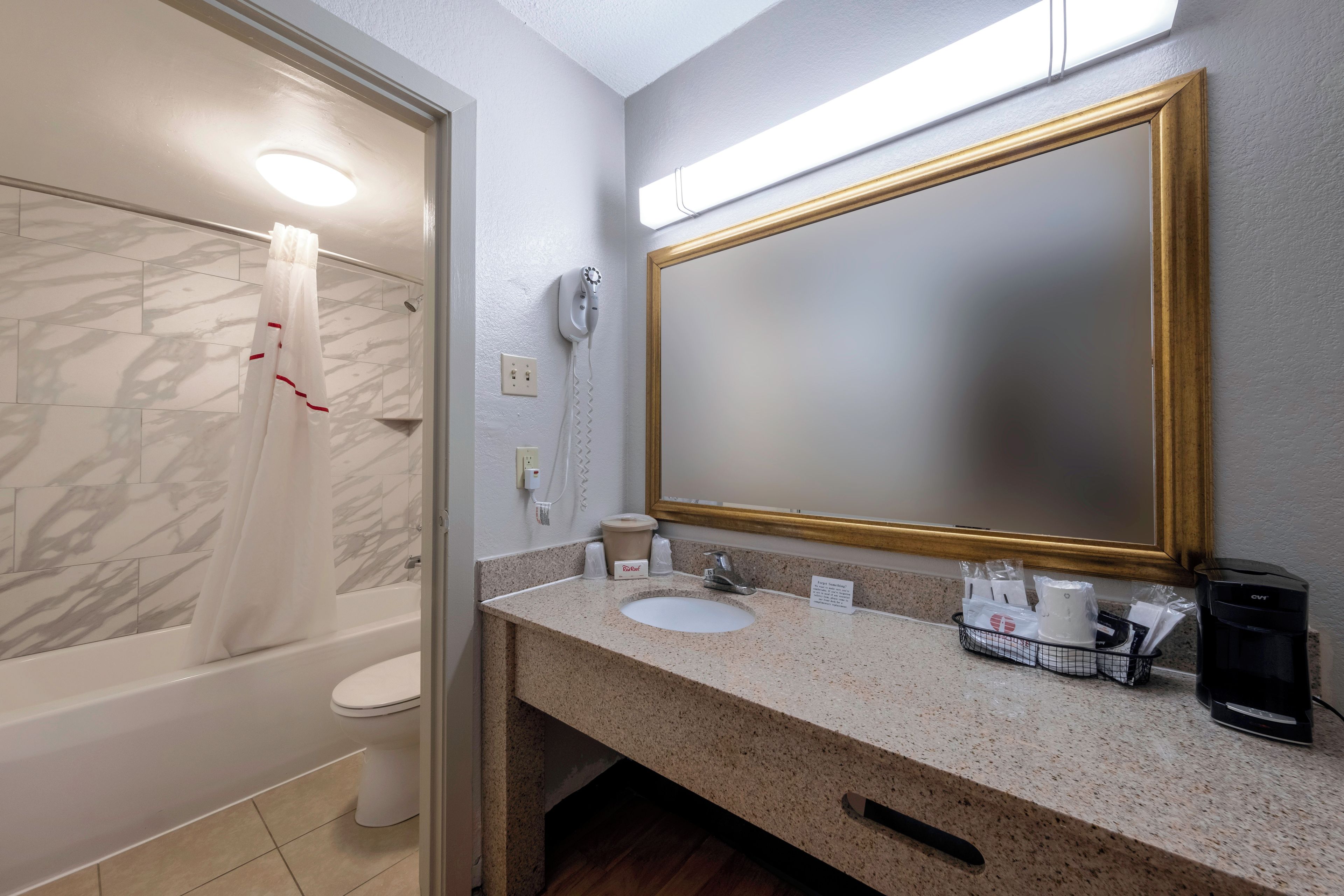 Ein Badezimmer mit Badewanne, Toilette, Waschbecken und einem großen Spiegel.