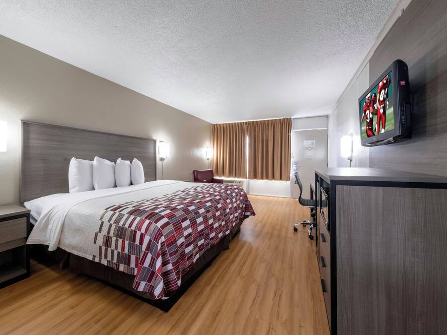 Una habitación de hotel con cama, escritorio, televisor y armario.