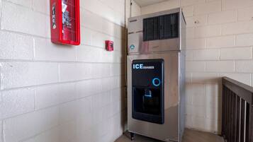 Una máquina expendedora con dispensador de hielo, extintor y termostato instalado en la pared.