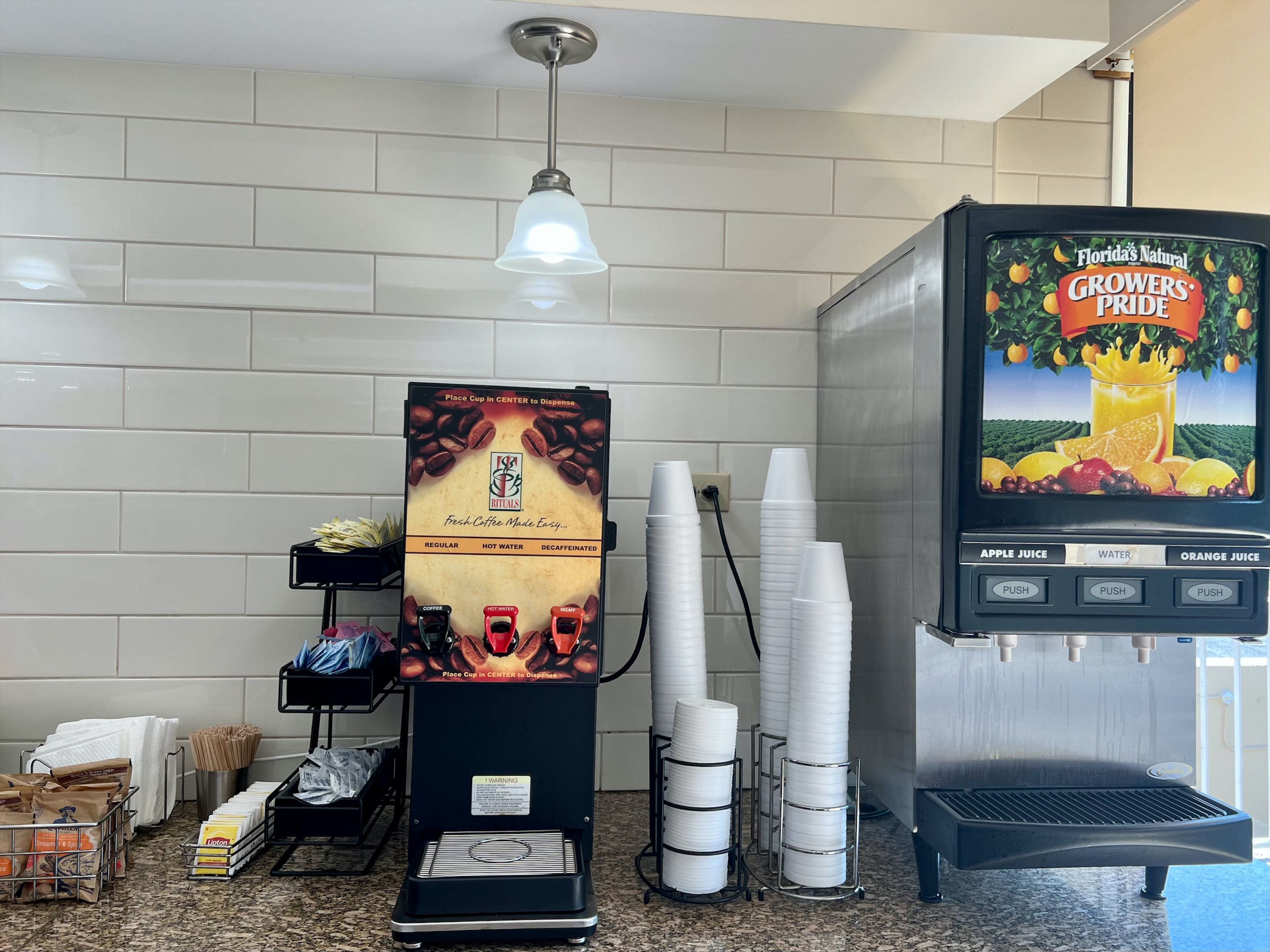 Una máquina de café con dispensador, tazas apiladas y pantalla de selección de bebidas.