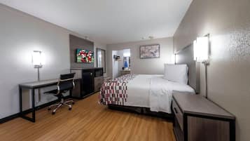 A hotel room with a bed, desk, chair, and a television.