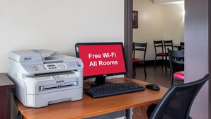 Ein Arbeitsplatz mit Drucker, Computer und Schild, das kostenloses WLAN anzeigt.