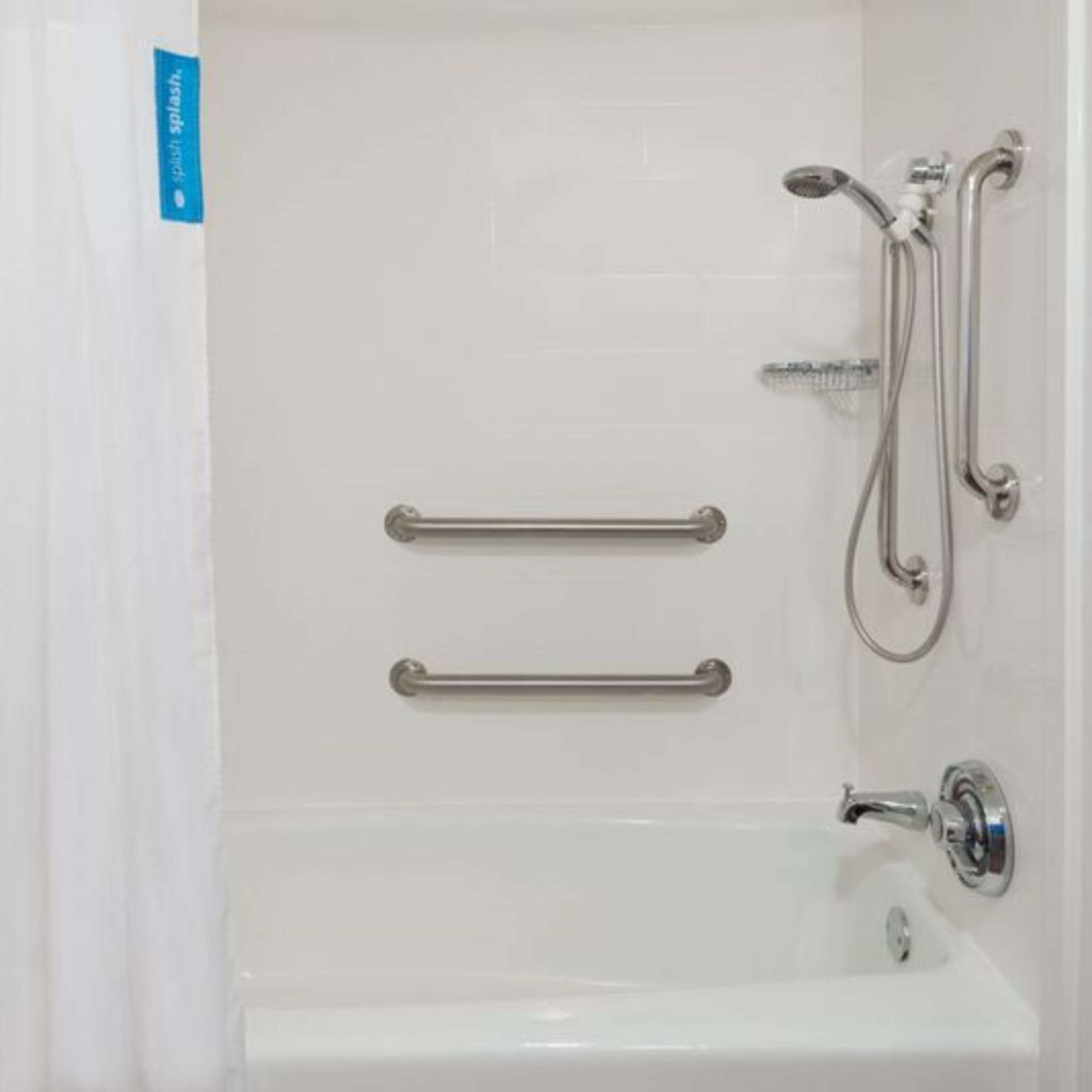 A white bathtub with two grab bars, a showerhead, and a faucet.