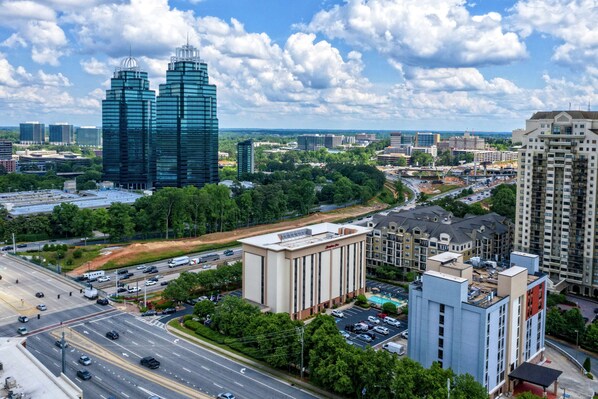 A cityscape with modern buildings, a large intersection, and surrounding greenery.