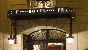 The entrance to Hotel Franco with a black wrought iron gate and a sign above it. - Hôtel Francois 1er (Paris)