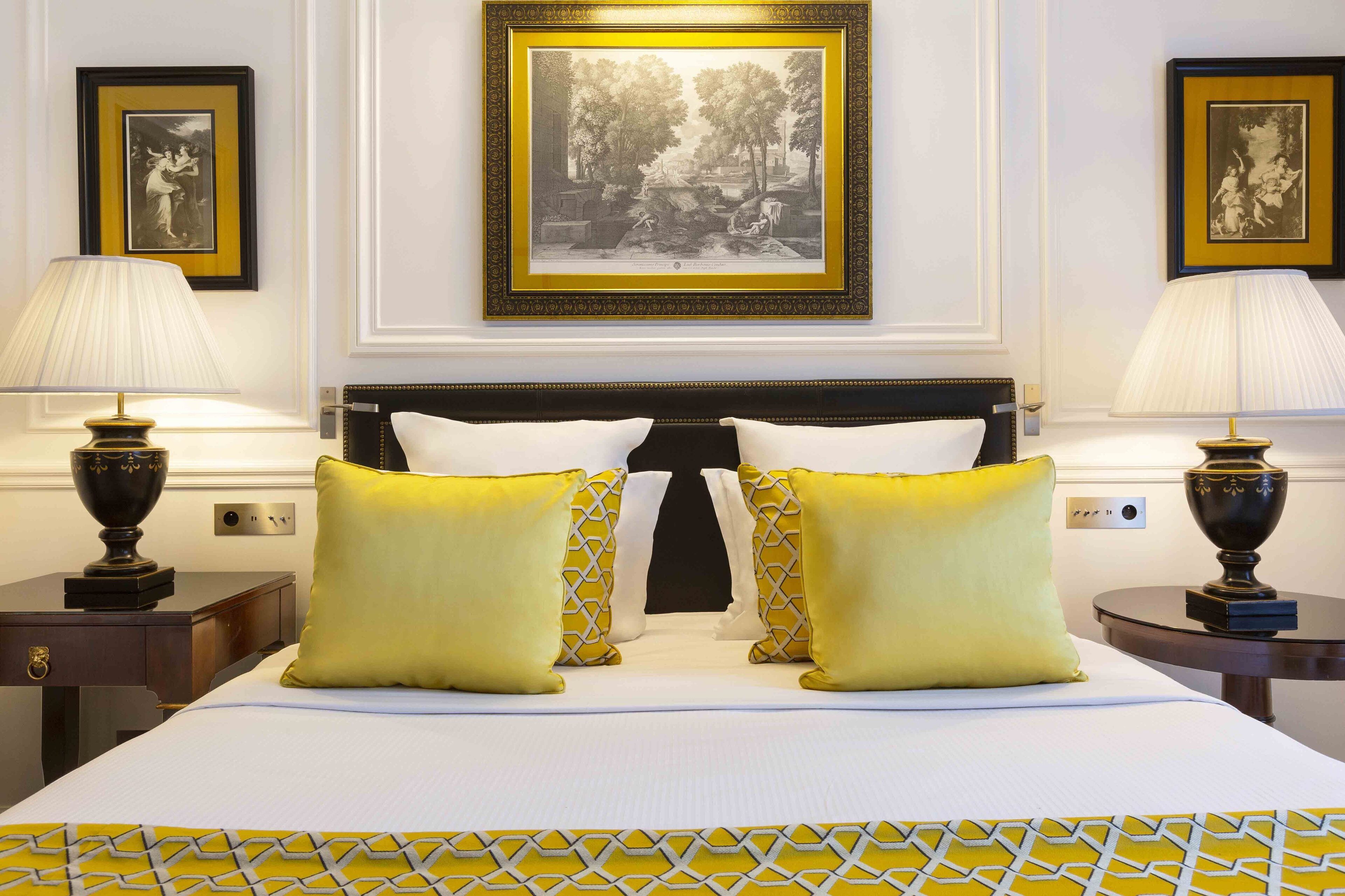 A neatly made bed with two pillows, a headboard, and two bedside tables with lamps.