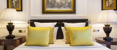 A neatly made bed with two pillows, a headboard, and two bedside tables with lamps.